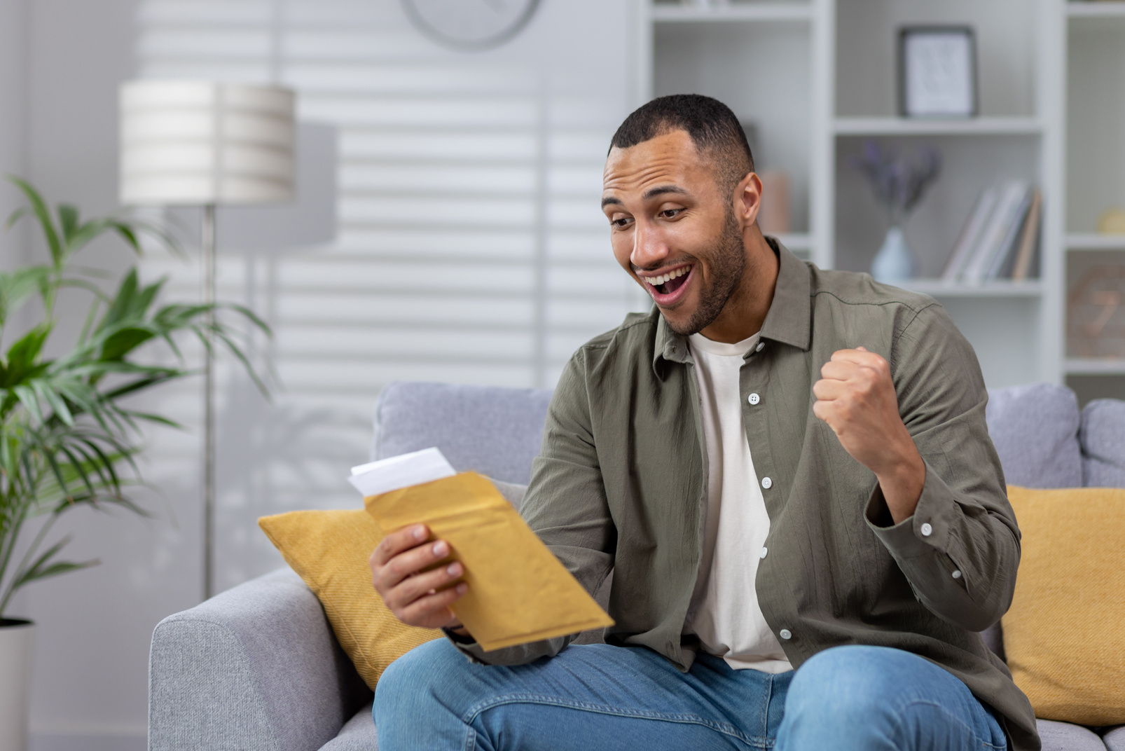 A happy young Muslim man reads good news from a letter, holds documents in an envelope. Celebrates victory, received credit, monetary reward, citizenship, promotion